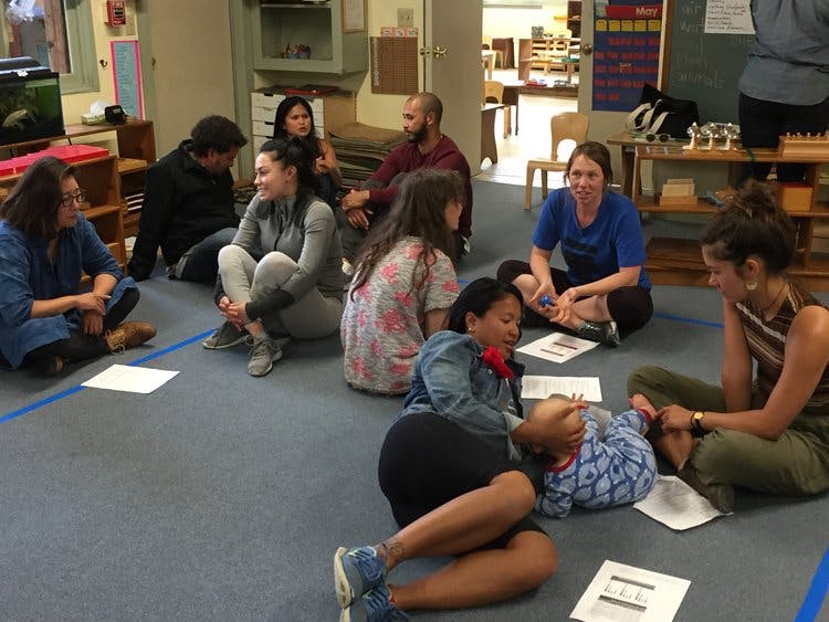 Group of people sitting on the floor in a classroom