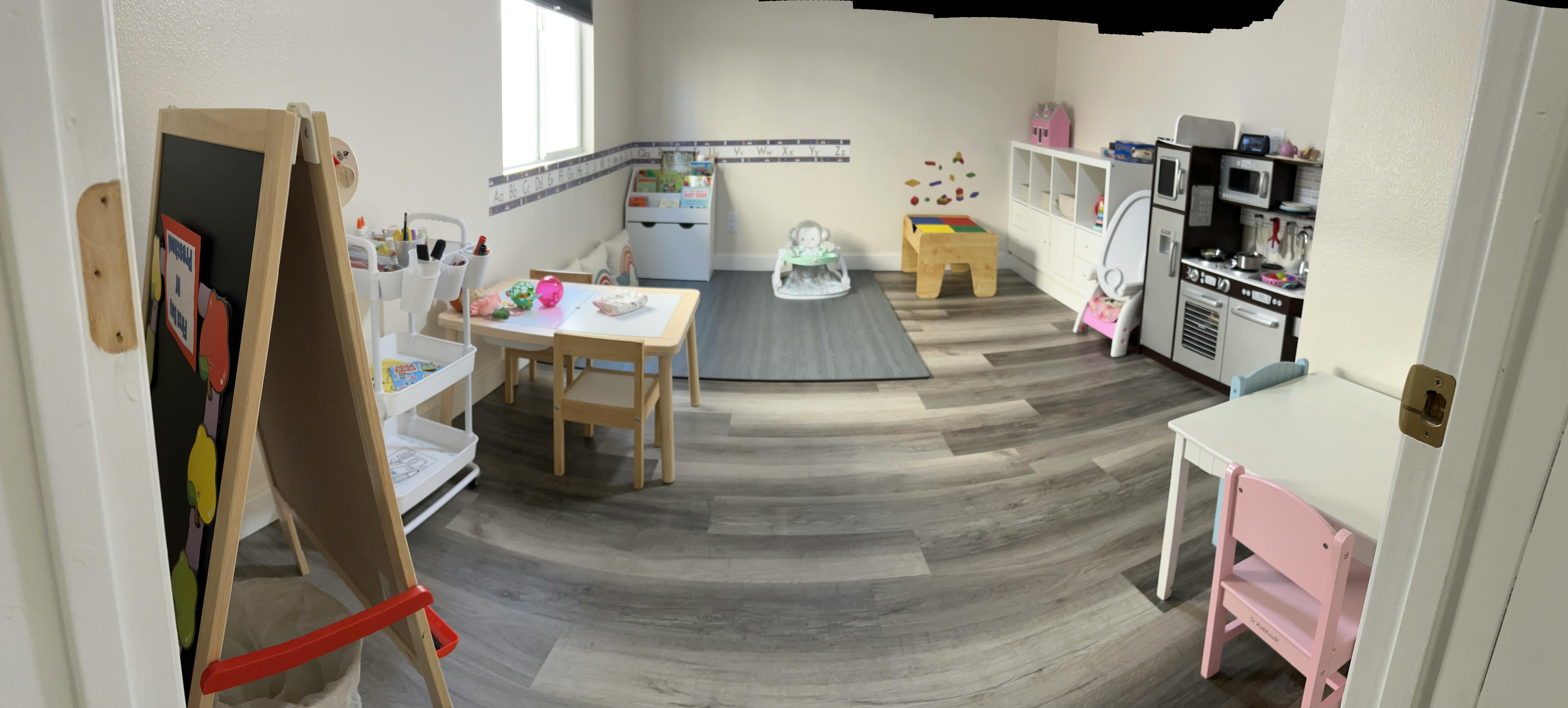 Playroom with small tables, chairs, and a toy kitchen