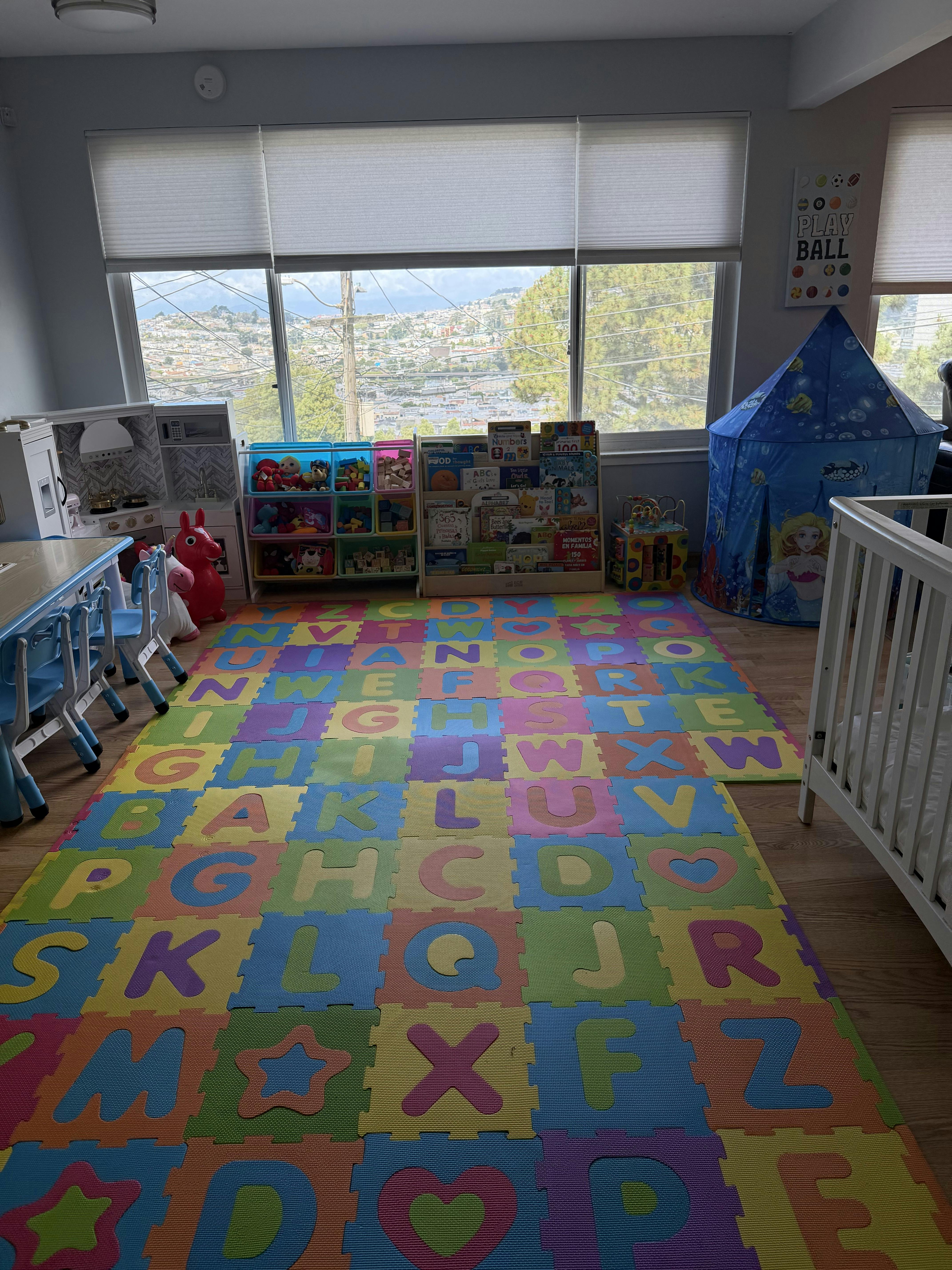 Colorful alphabet floor mats in a child playroom with toys and a play tent