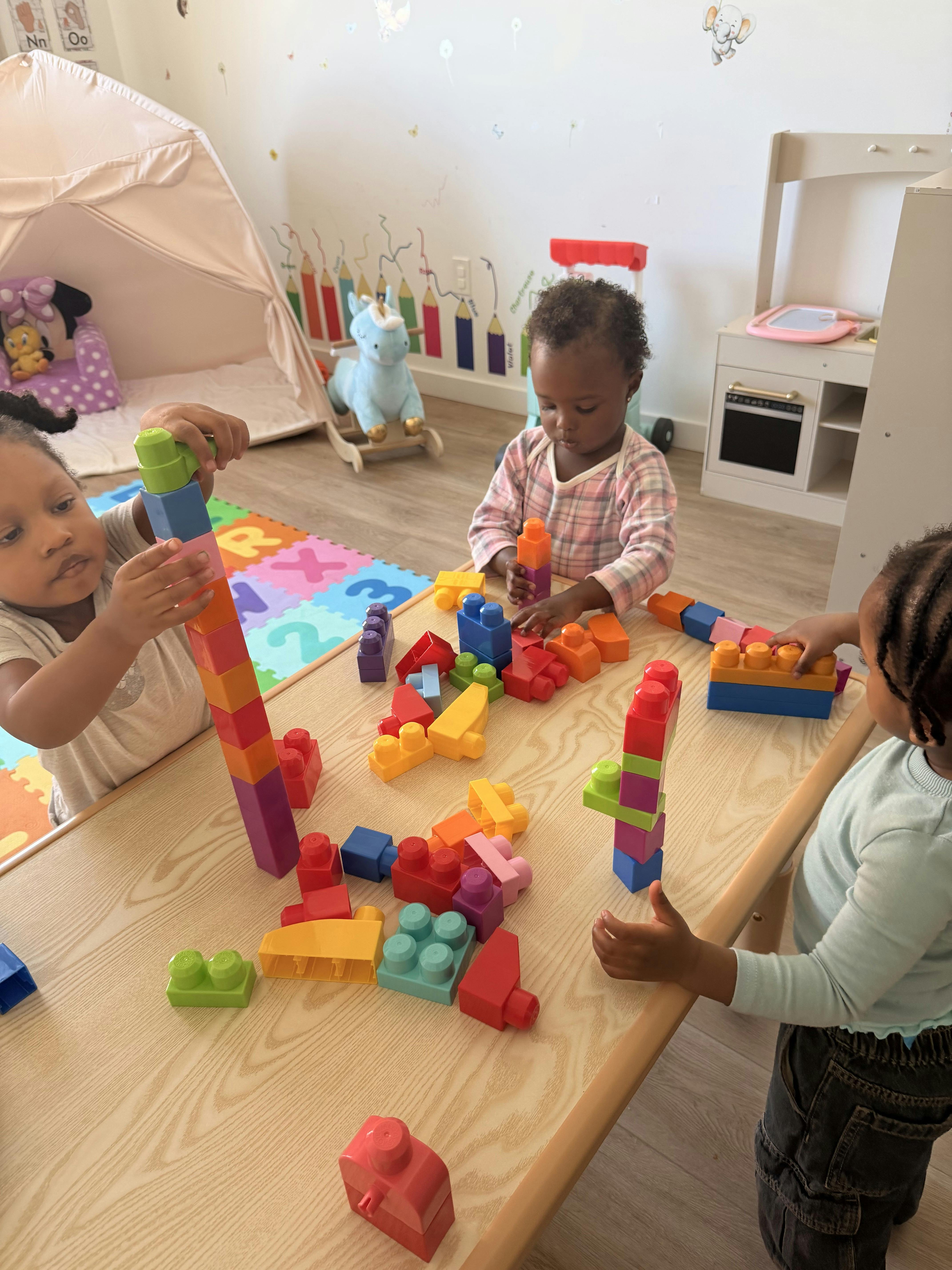 Three children building with plastic blocks on a table