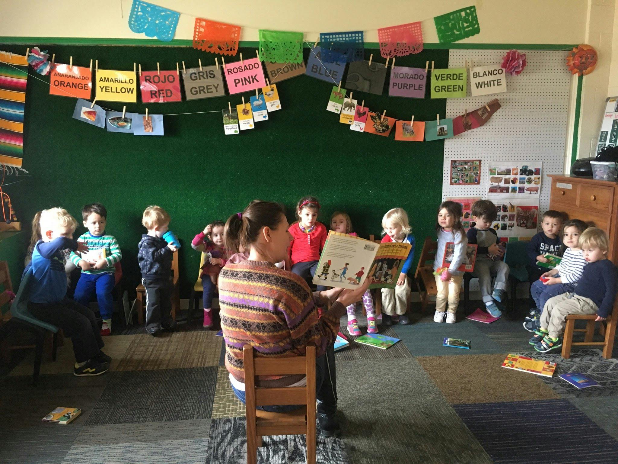 Person reading a book to a group of children in a classroom
