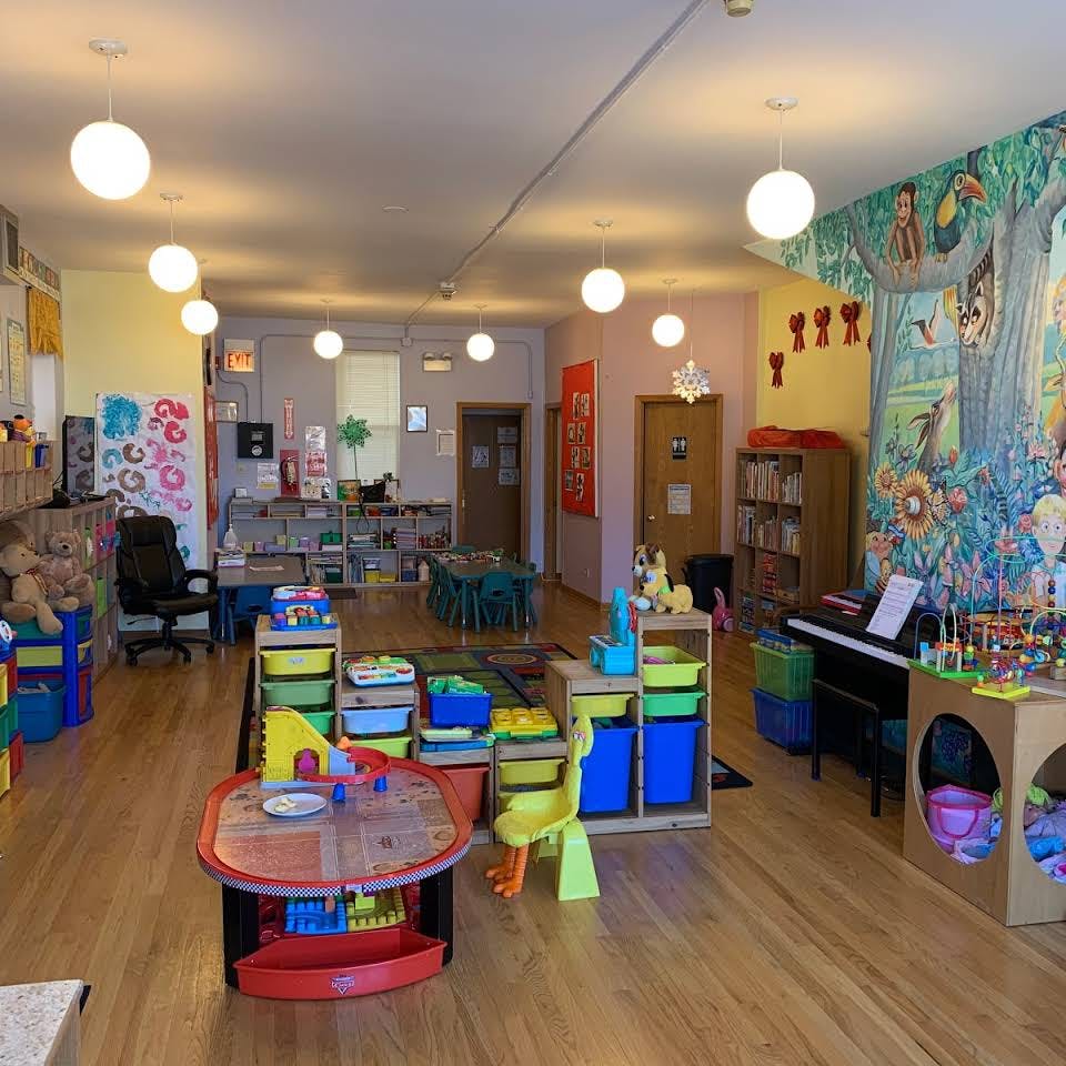 Playroom with colorful toys, small tables, and a mural on the wall