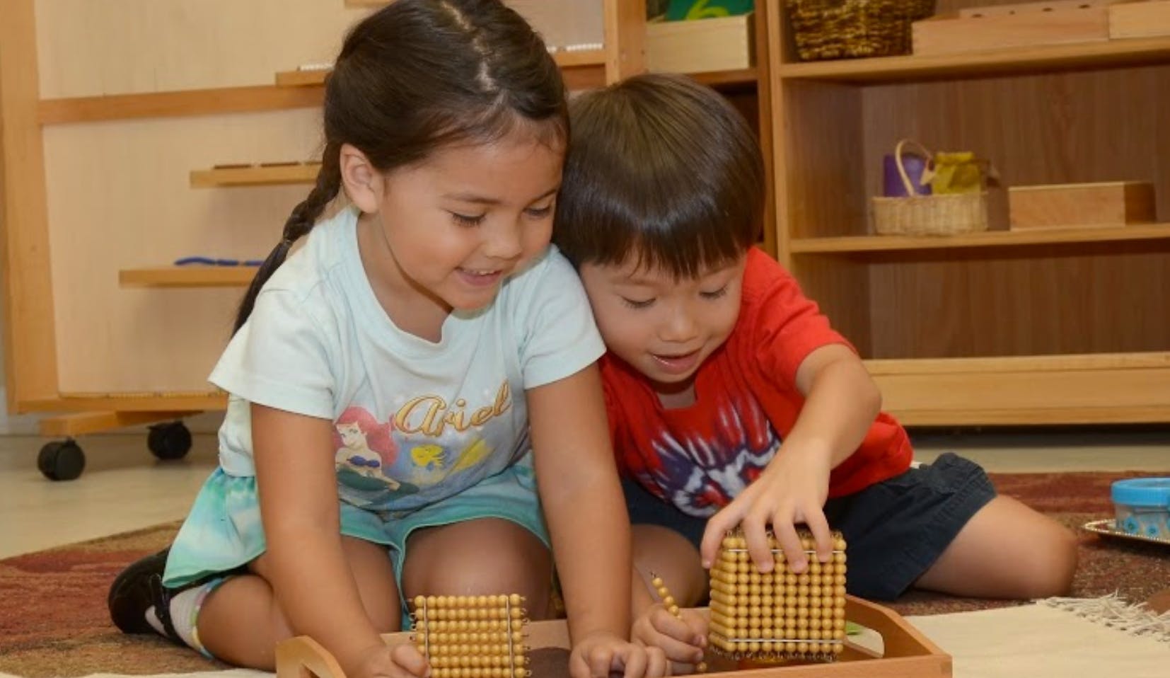 Two children playing with wooden blocks on the floor
