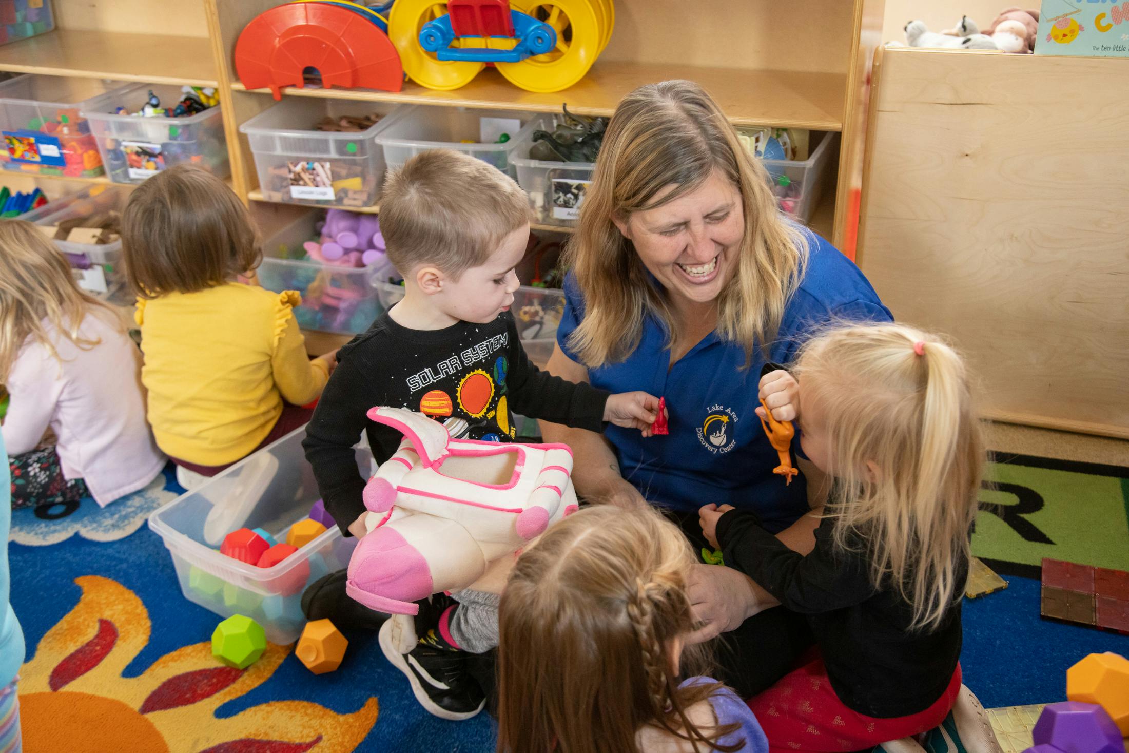 Adult and children playing with toys in a classroom