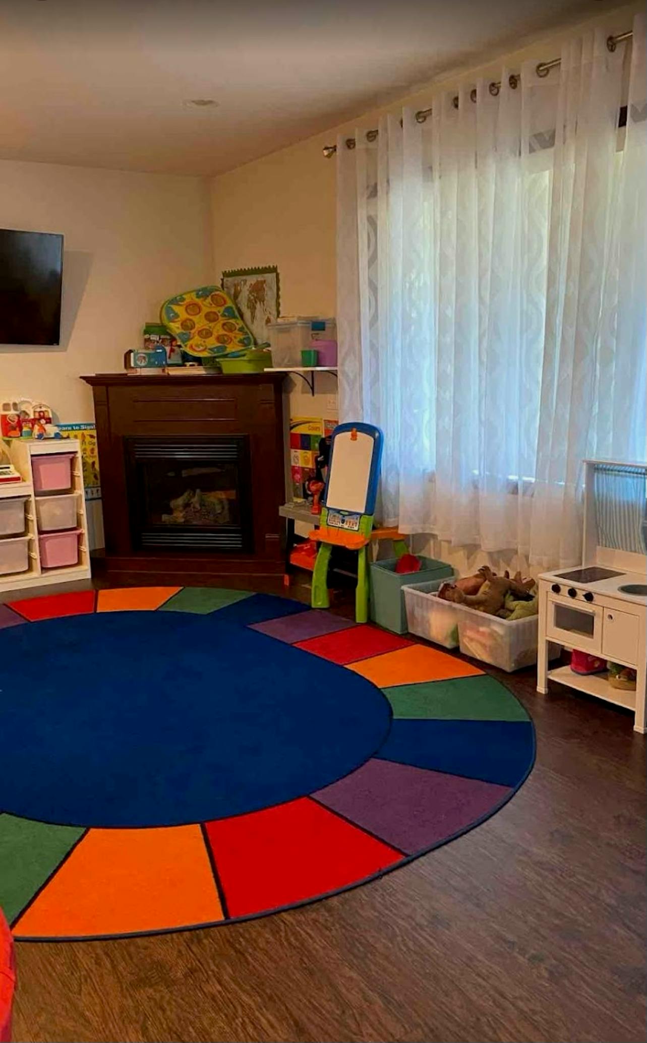 Colorful circular rug in a children's play area with toys and a fireplace