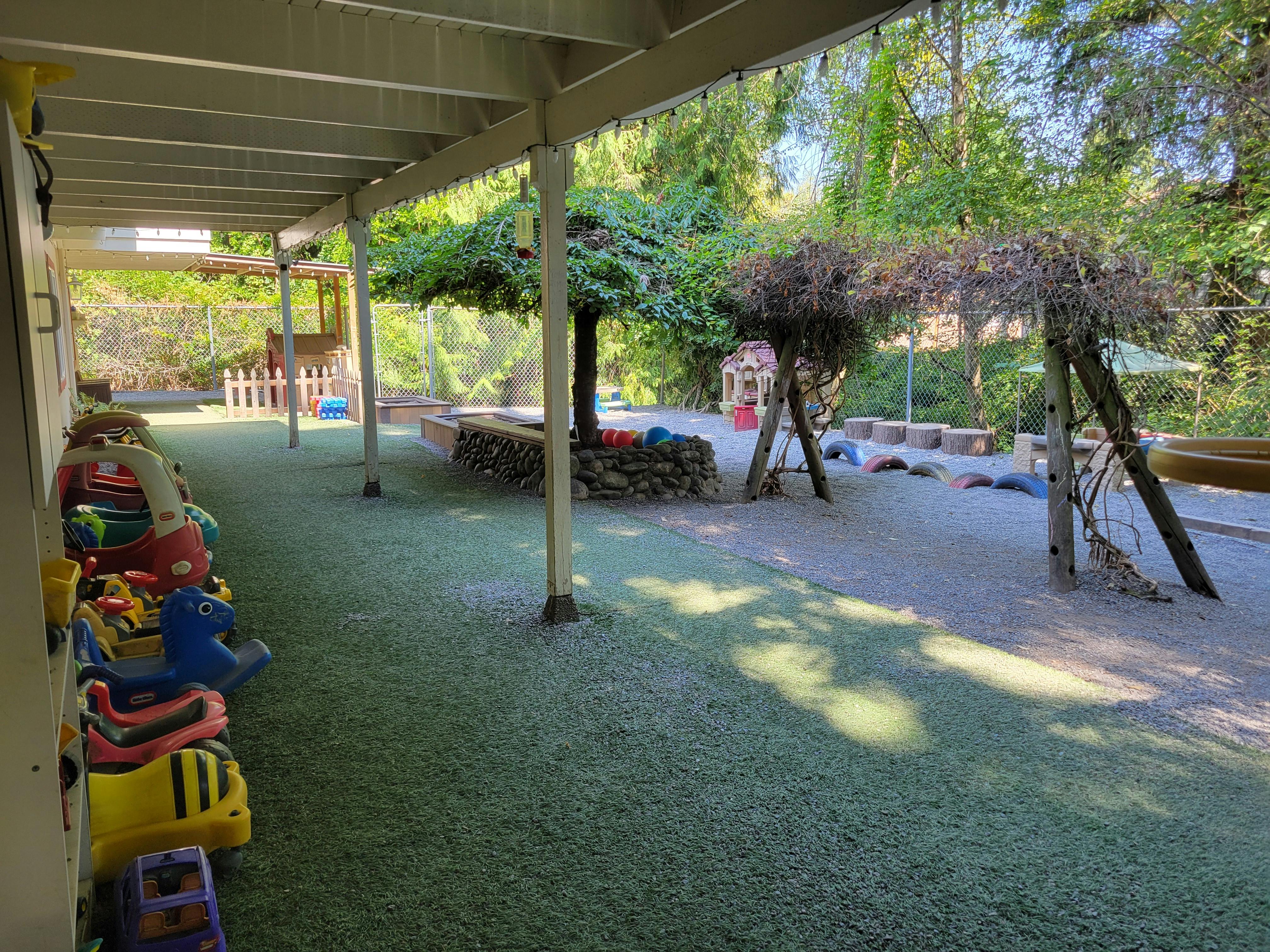 Outdoor playground with artificial turf, ride-on toys, and natural play structures