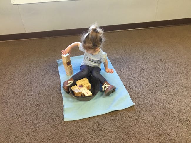 Child playing with wooden blocks on a mat