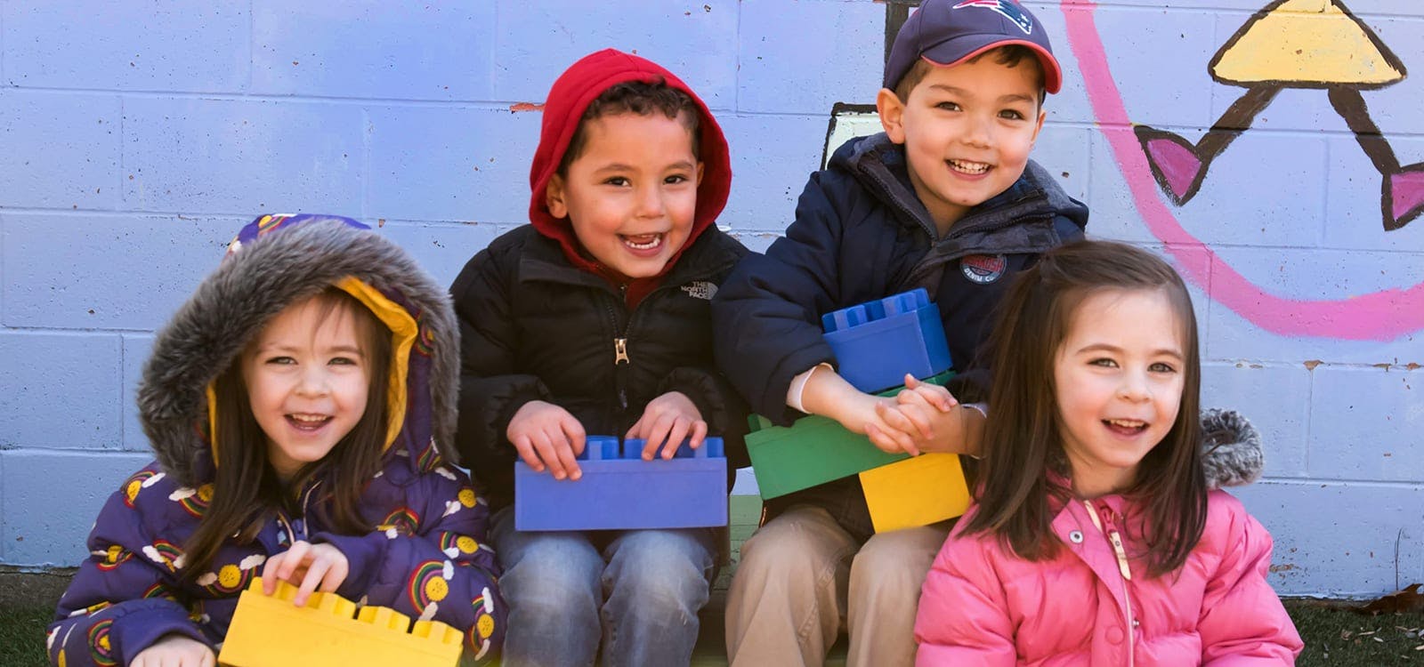 Four children holding colorful building blocks