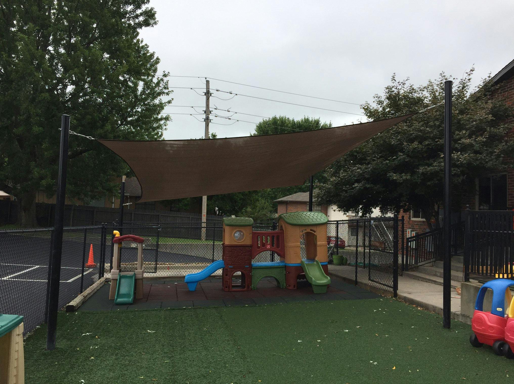 Playground with play structure, slides, and shade sail shade