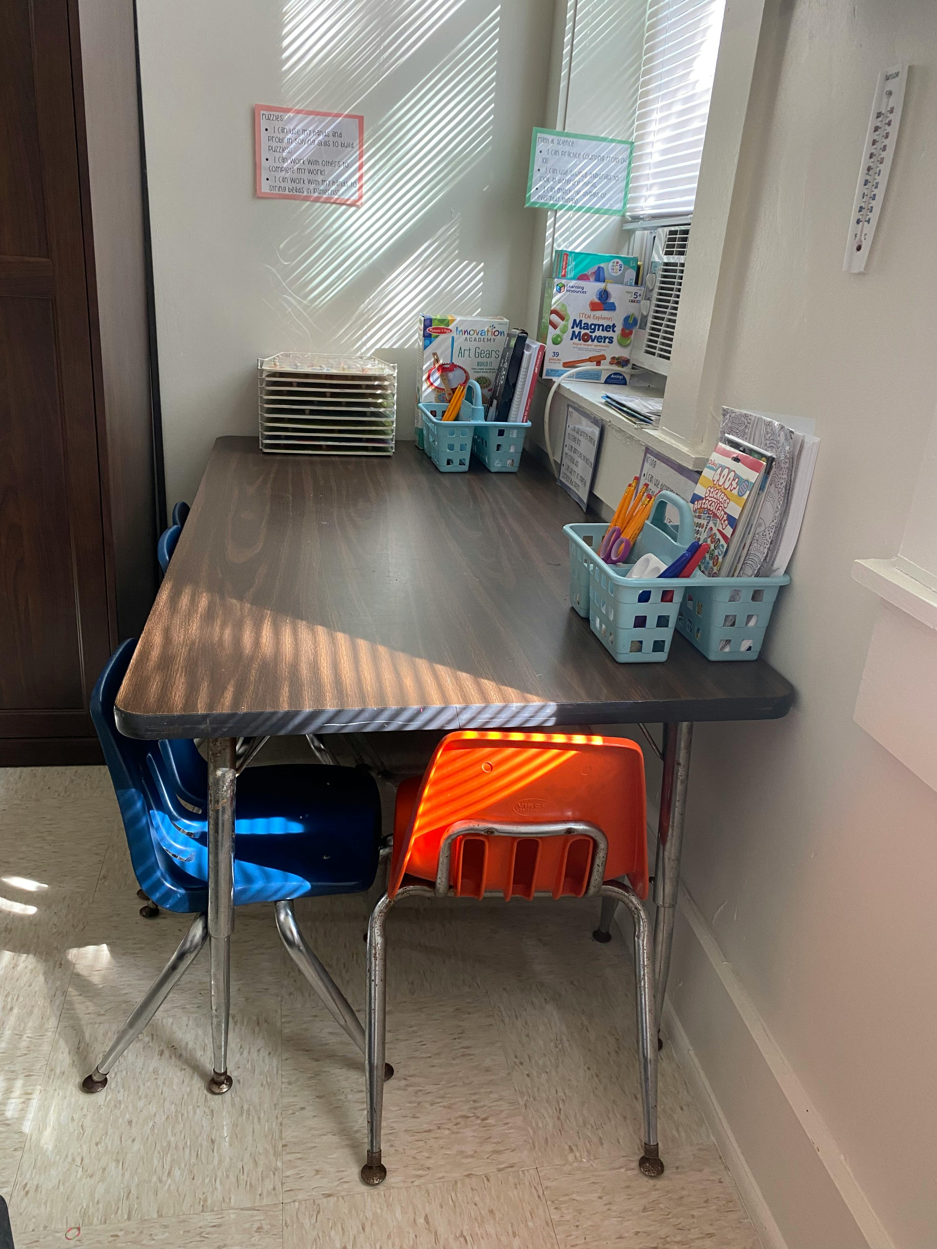 Classroom desk with two chairs and school supplies