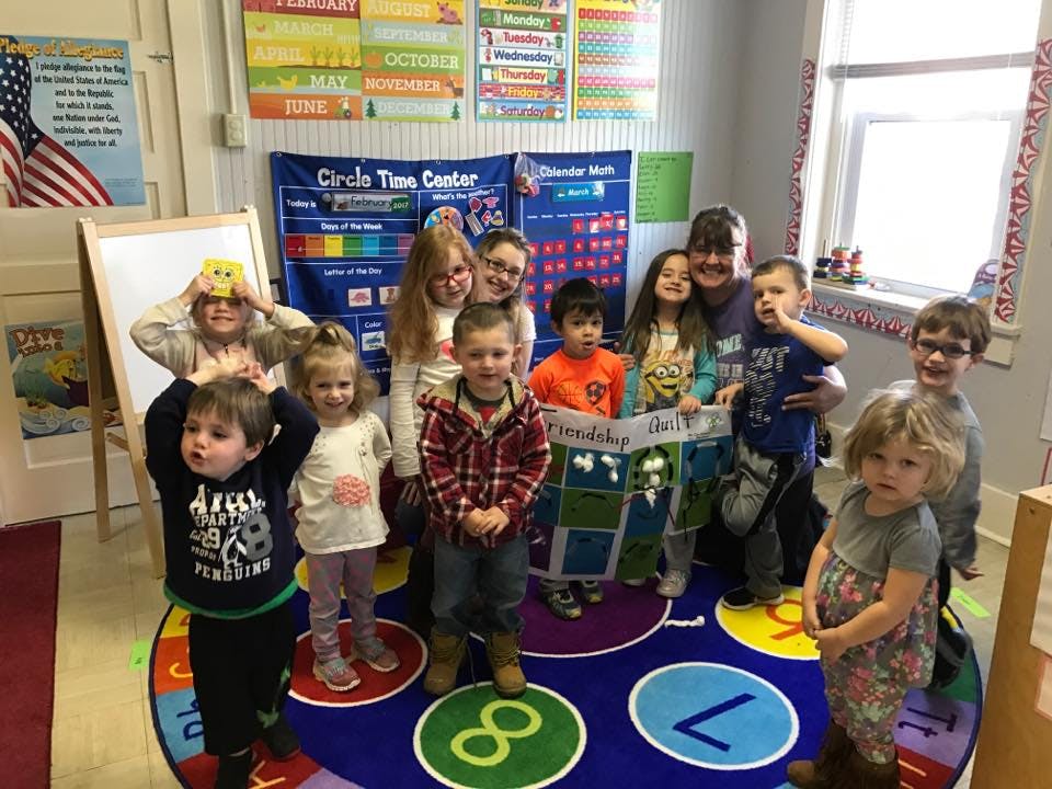 Group of adults and children posing in a classroom