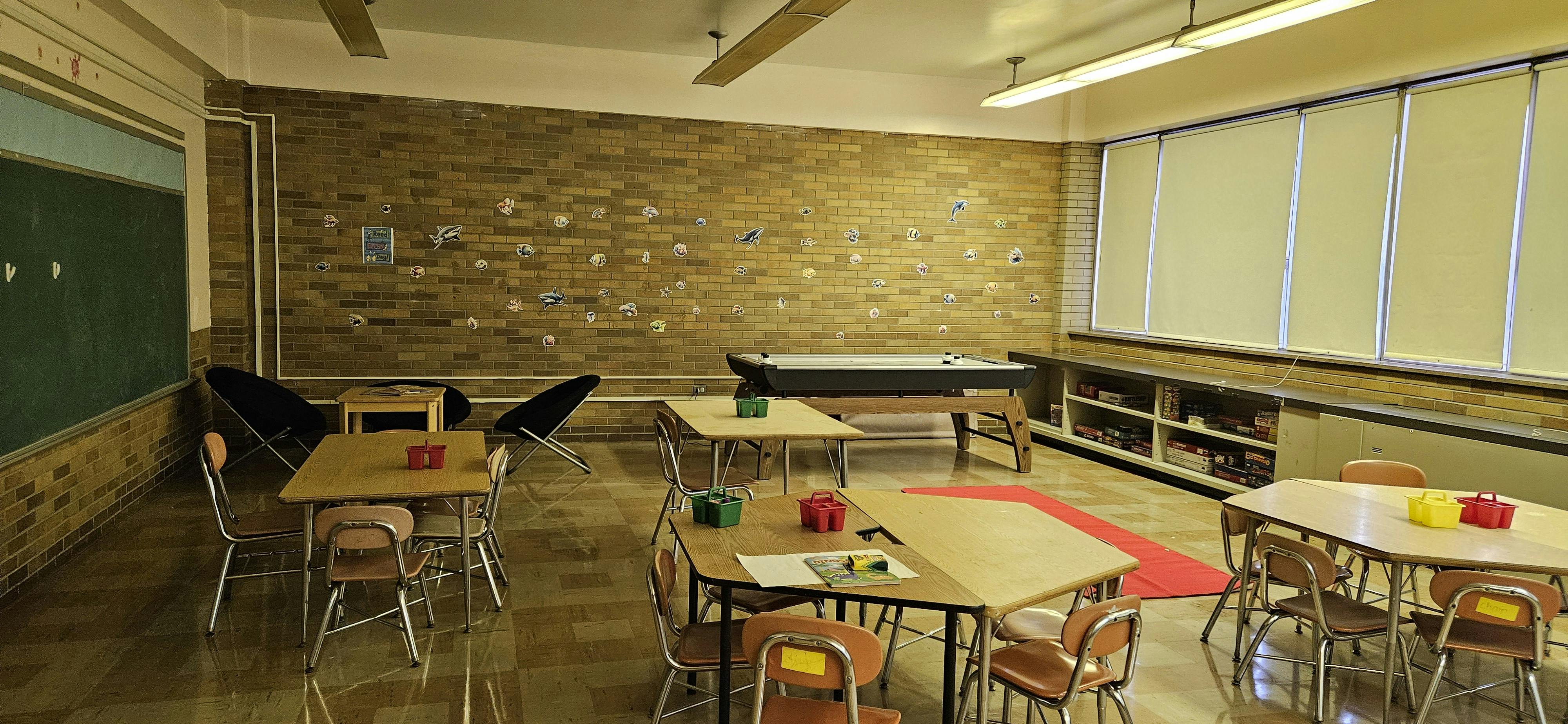 Classroom with tables, chairs, a chalkboard, and a pool table