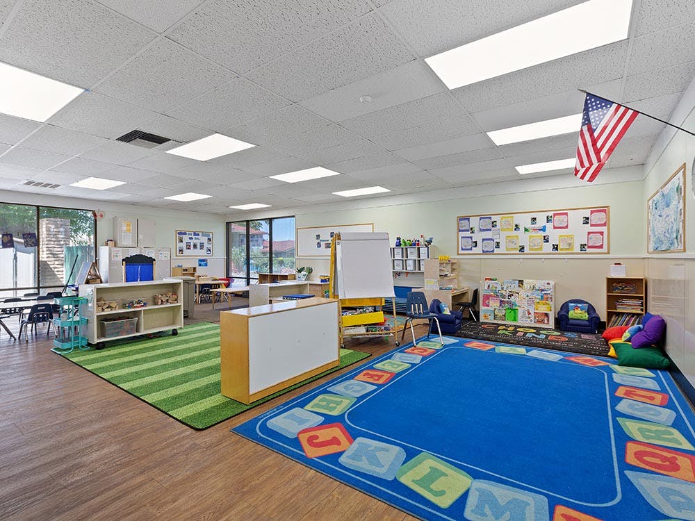 Empty classroom with two rugs, one blue with letters, and one green