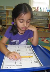 Child writing on paper with a pencil at a desk