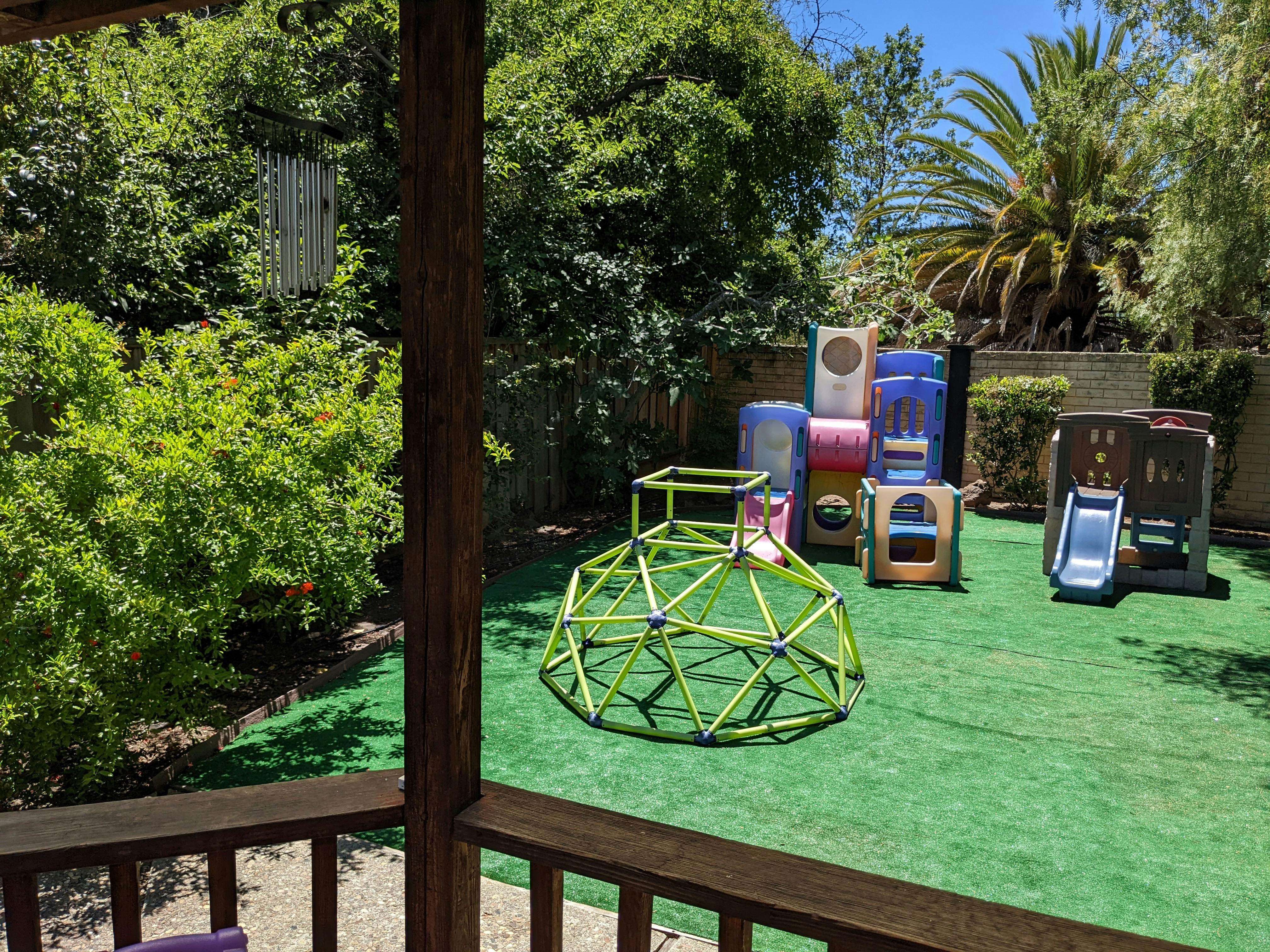 Backyard with green artificial turf and children's play equipment