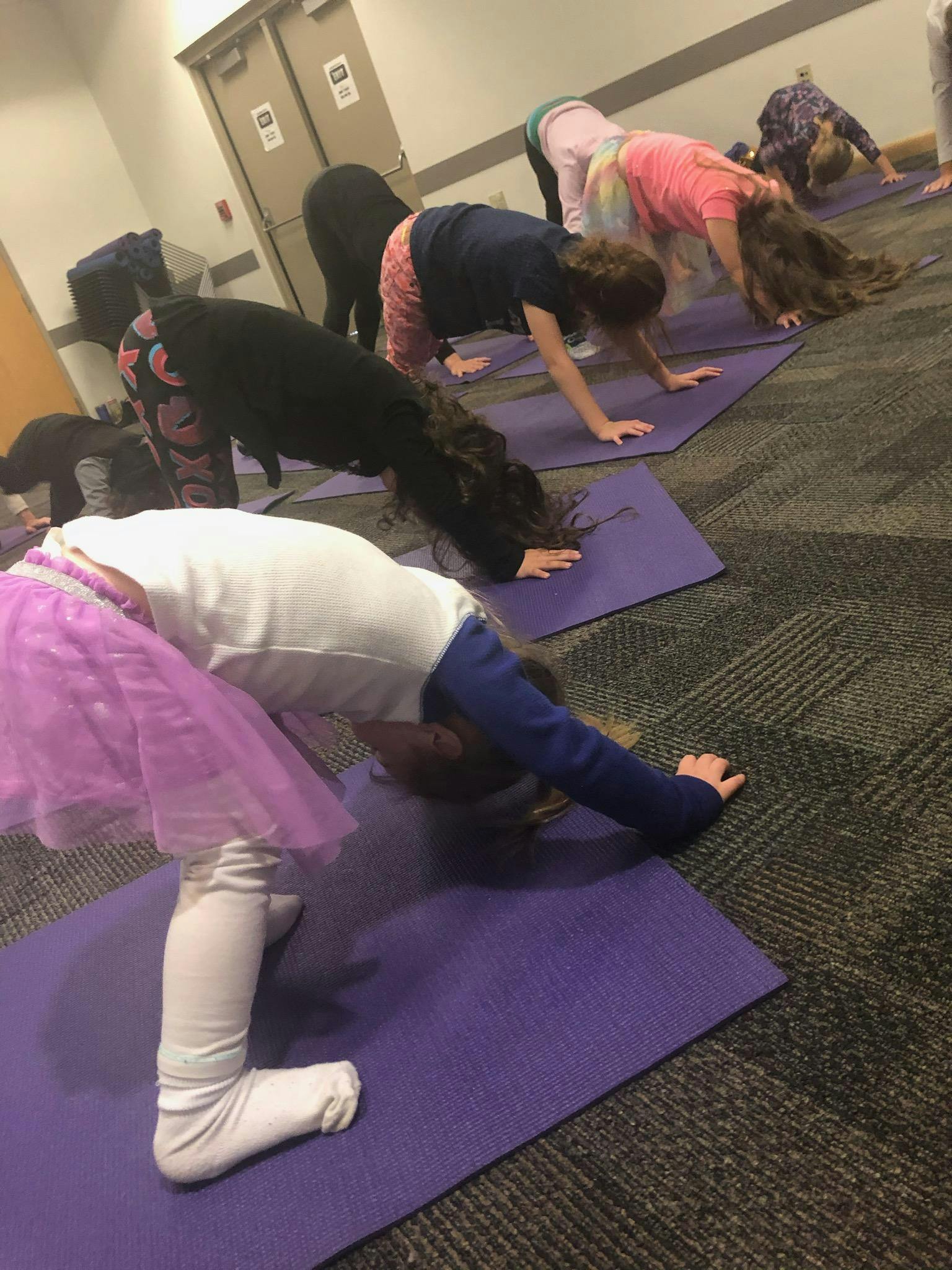 Children doing yoga poses on mats in a classroom