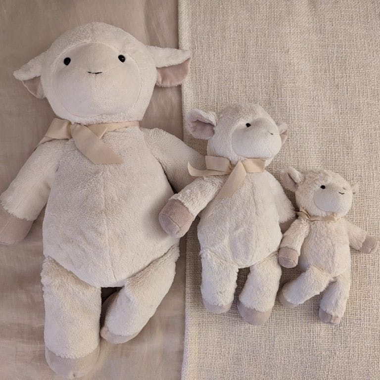Three white lamb stuffed animals of varying sizes