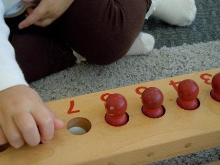 Child playing with a wooden number puzzle