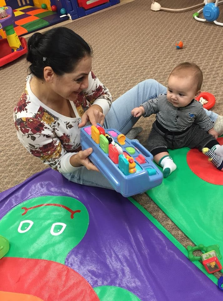 Person and child playing with a toy on the floor