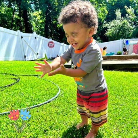 Child playing in a sprinkler on a sunny lawn