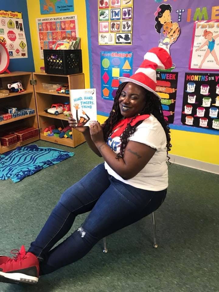 Person in a striped hat holding a book in a classroom