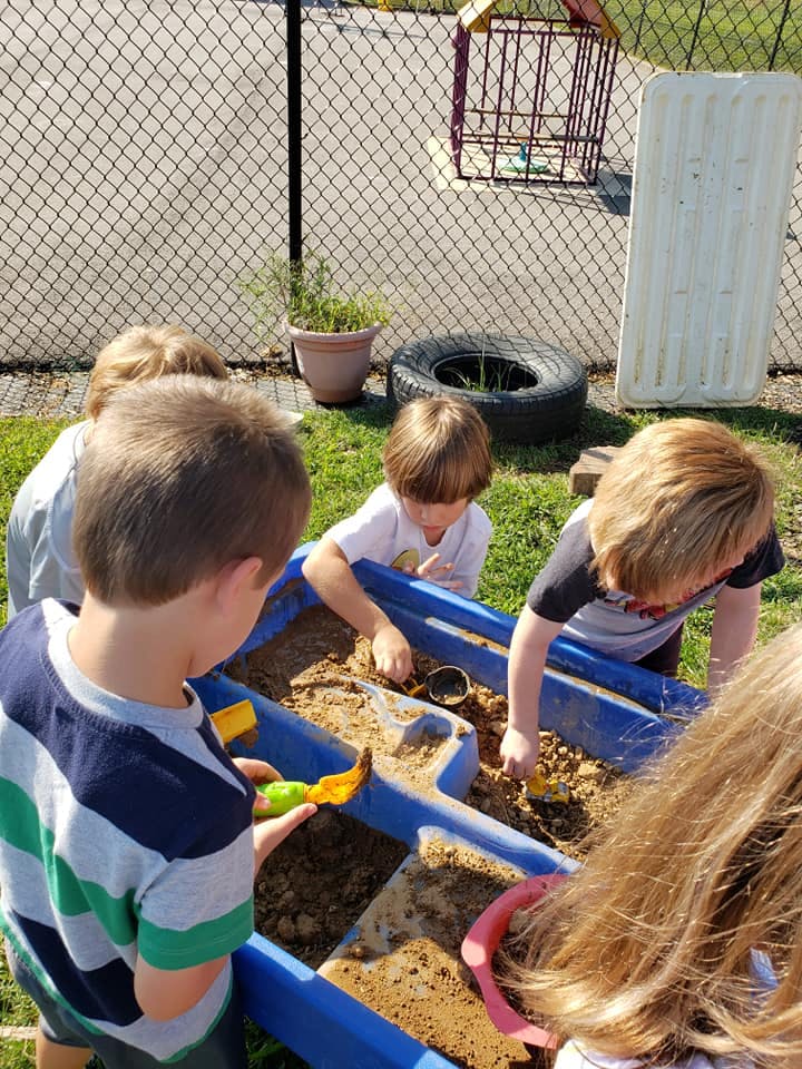 Children playing in a sand and water table outdoors