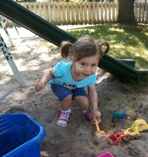 Child playing in a sandbox with a shovel