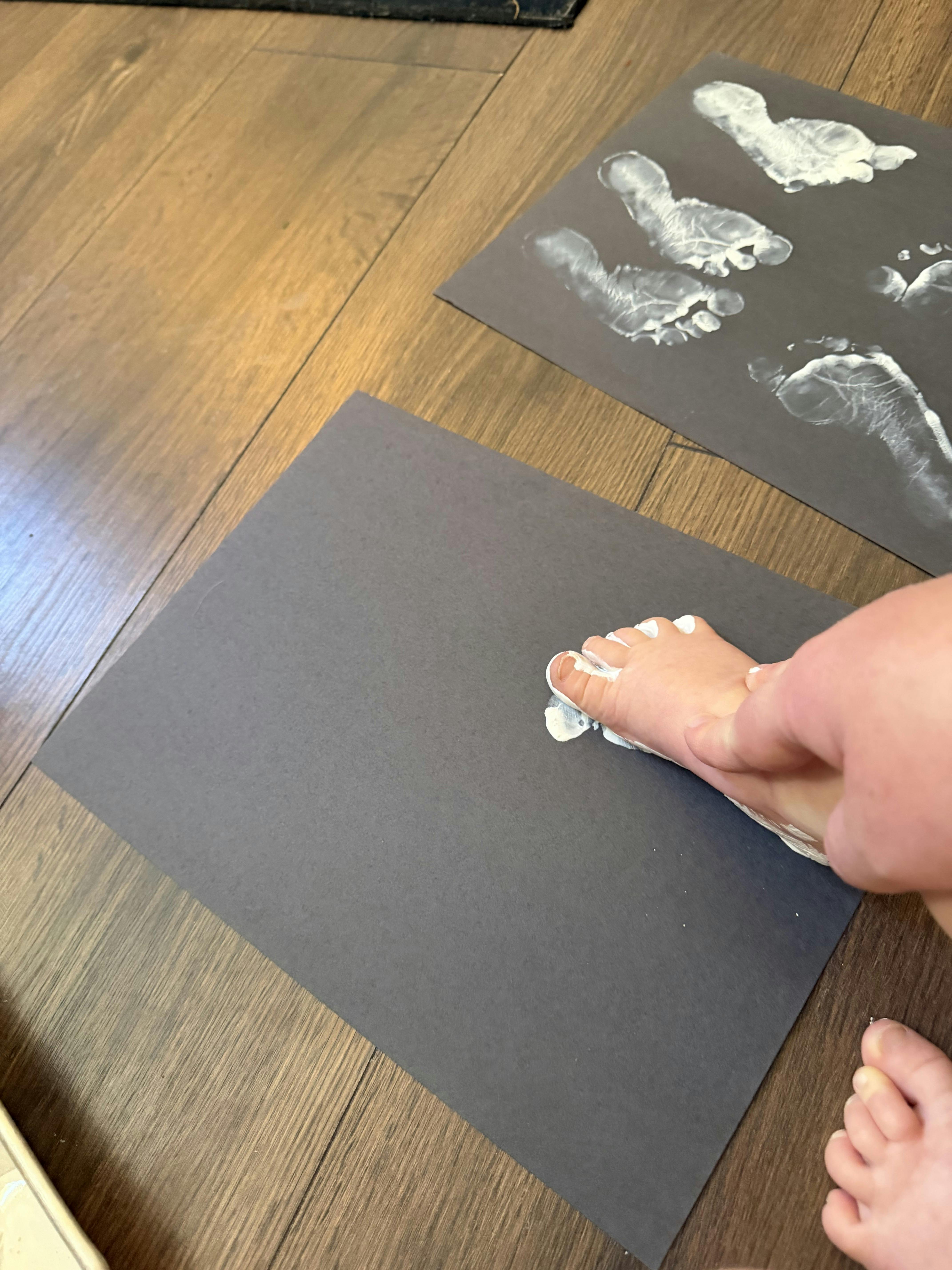 Child pressing painted foot onto black paper