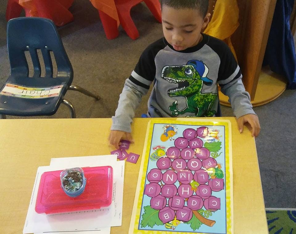Child playing with a letter puzzle on a table