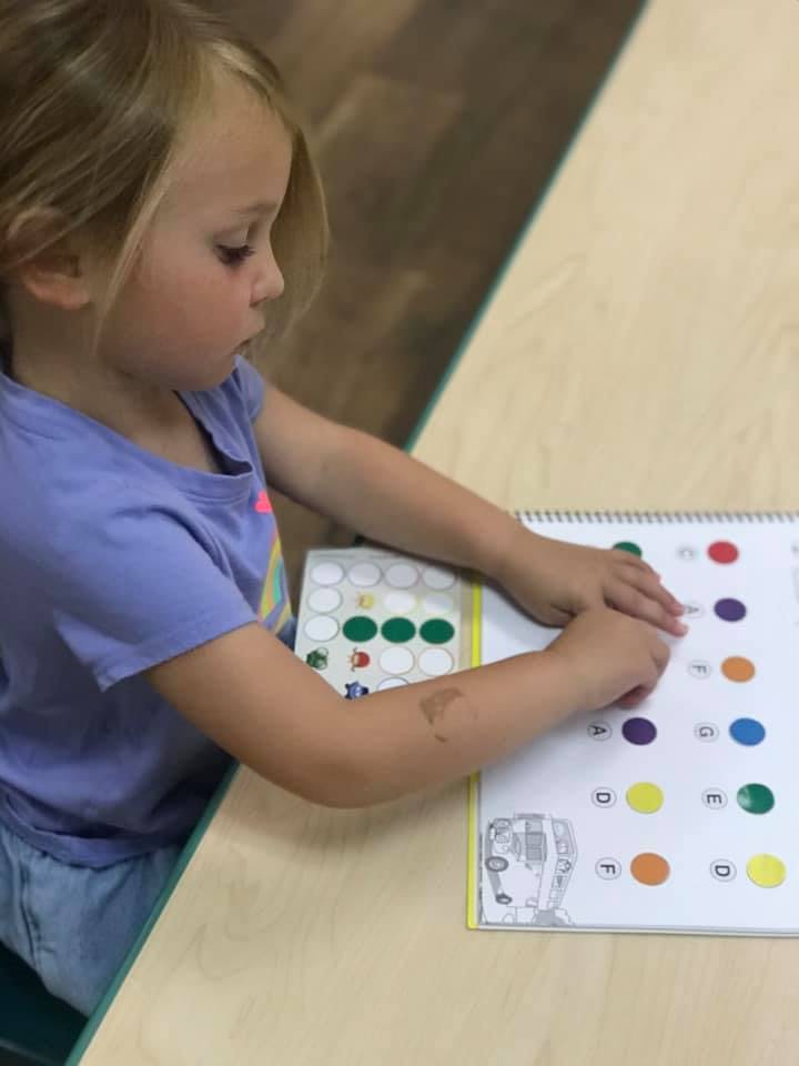 Child placing stickers on a workbook