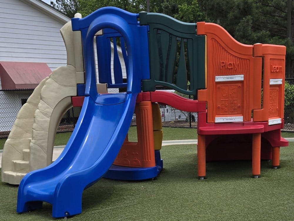 Colorful playground structure with a blue slide, steps, and panels that say "Play" and "Learn"