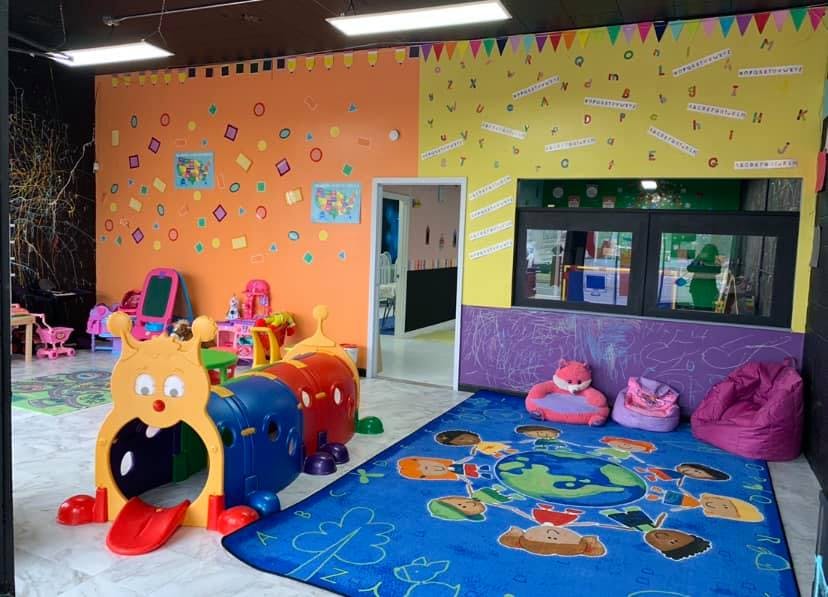 Indoor play area with colorful walls, play equipment, and a blue rug