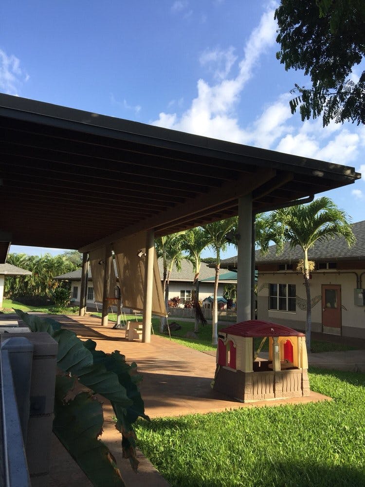 Covered walkway with palm trees and buildings in the background