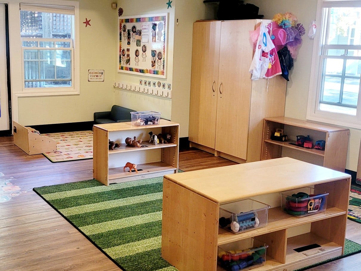 Classroom with low shelves of toys, rug with letters, and a "calming corner" sign