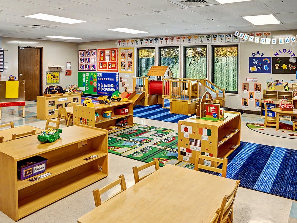 Colorful preschool classroom with play area, small tables, chairs, and learning materials