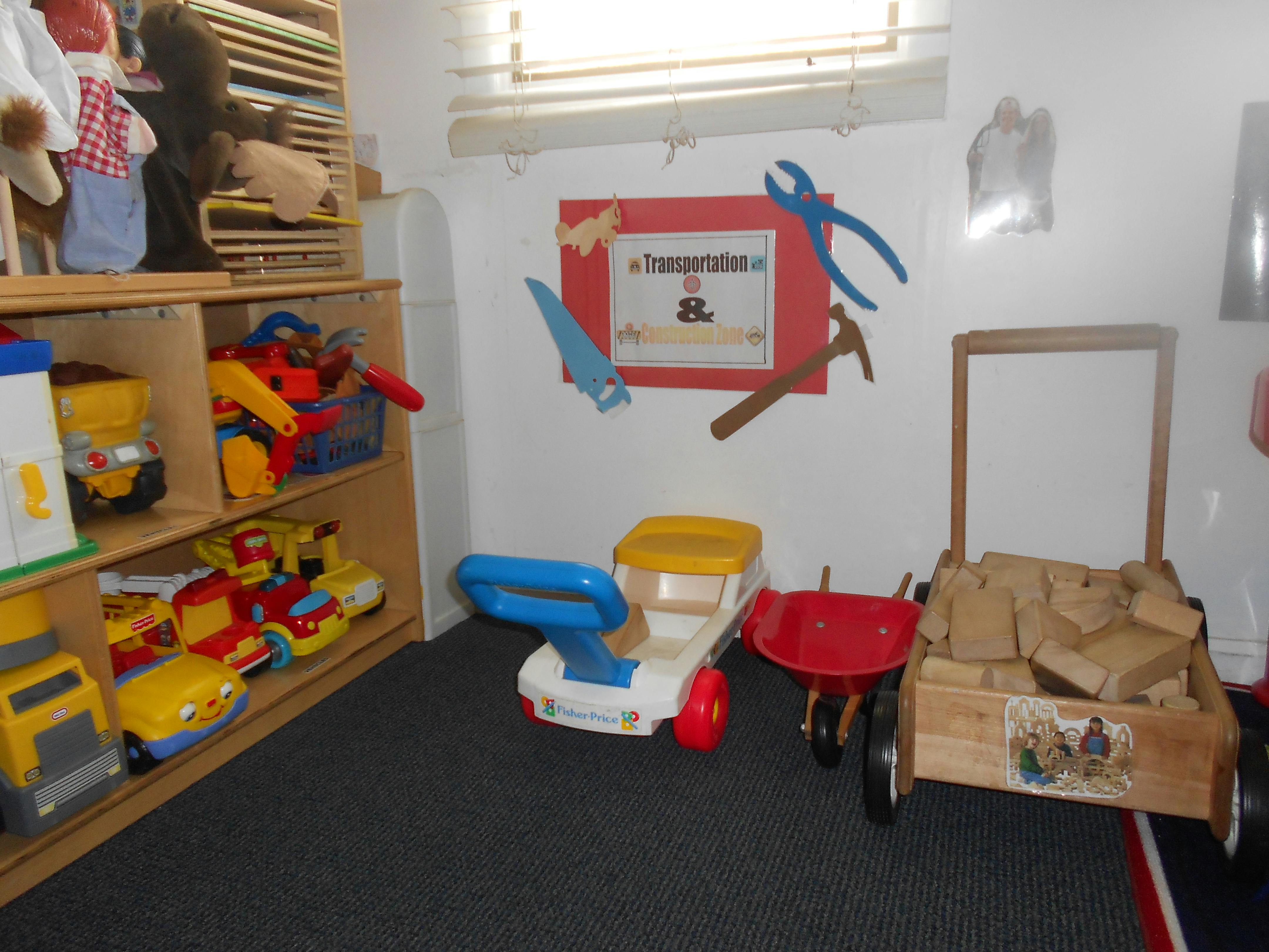 Children's play area with toy vehicles, tools, and a wooden wagon