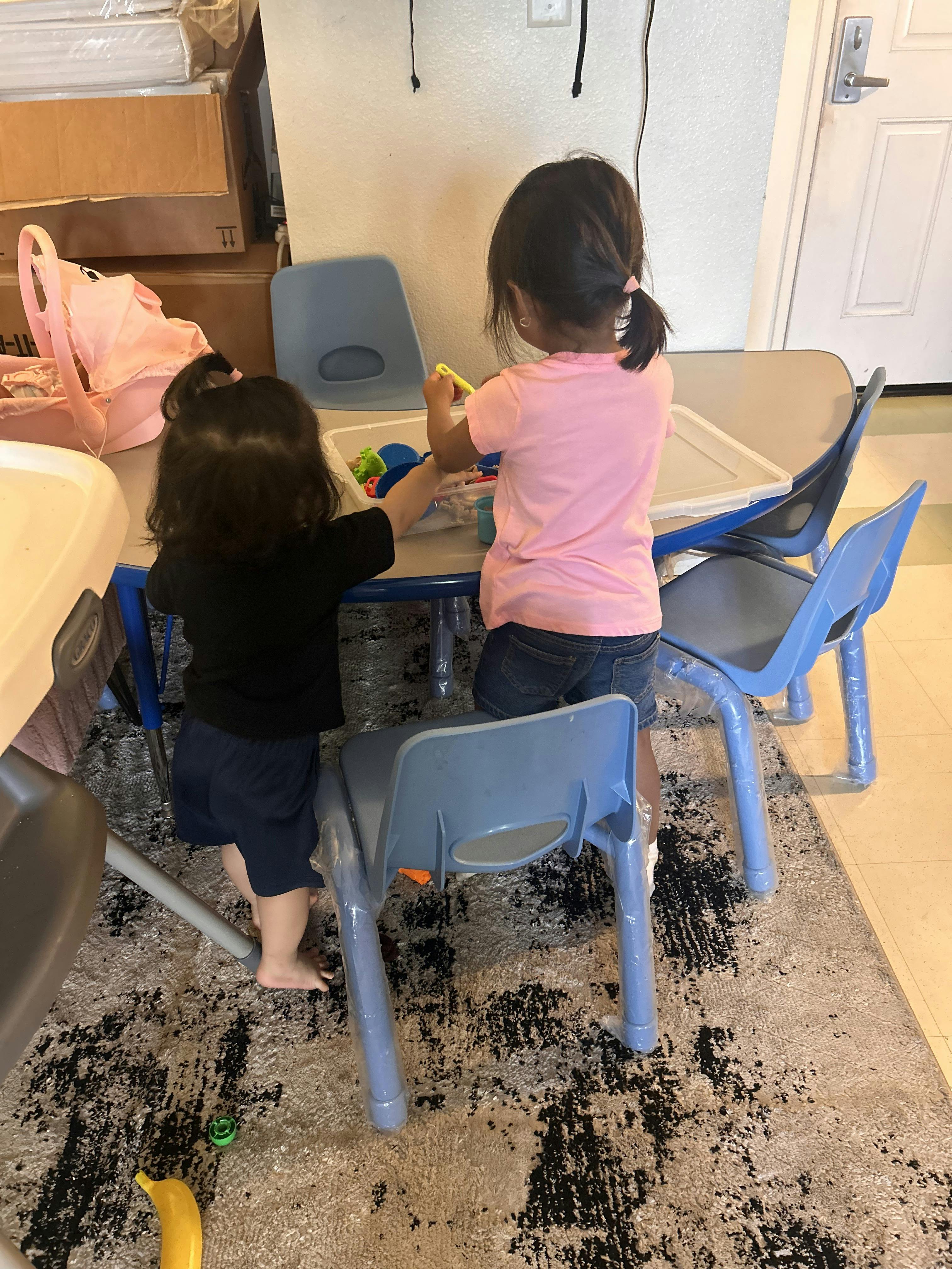 Two children standing at a table playing with toys
