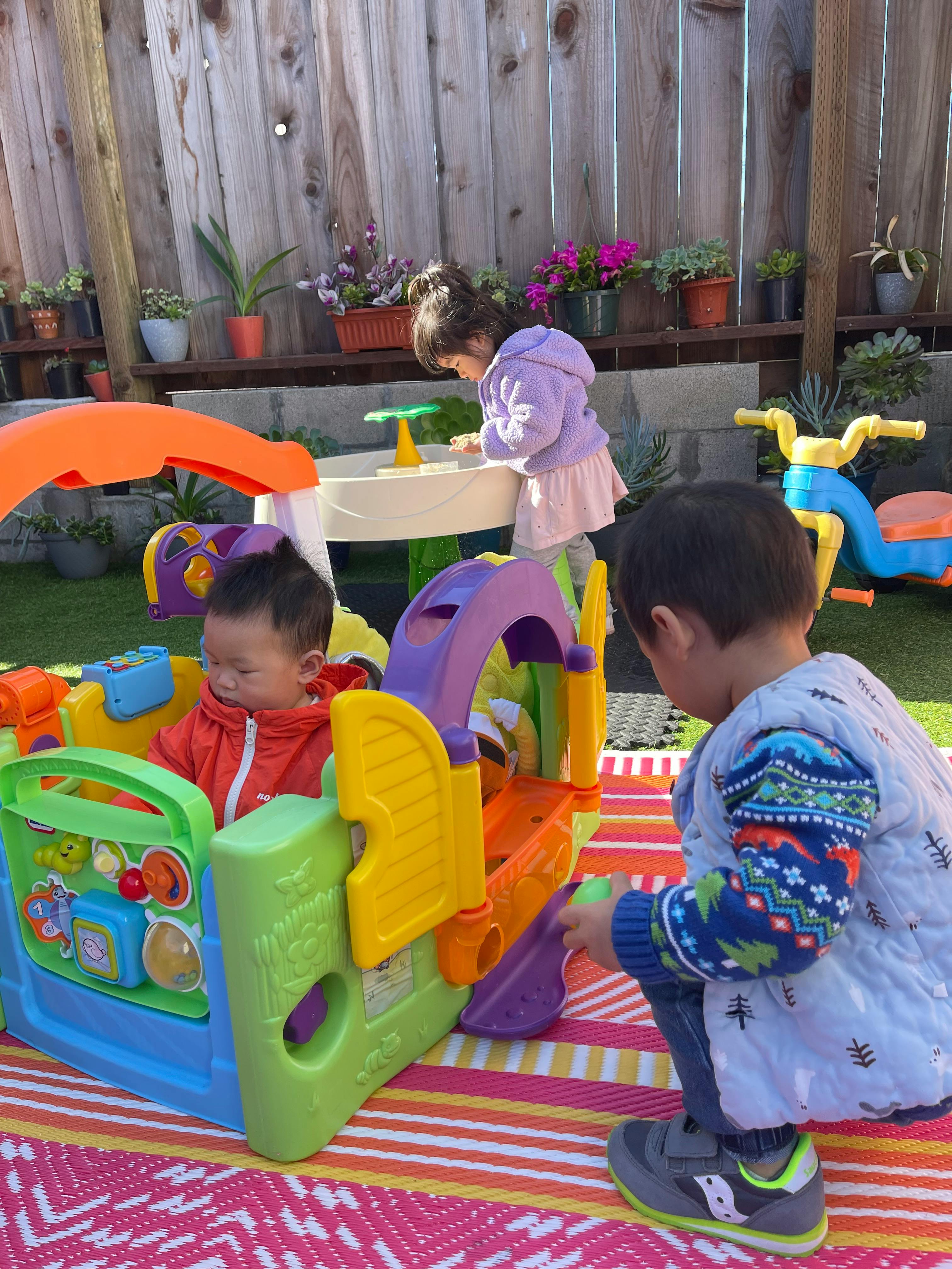 Three children playing with colorful toys outdoors