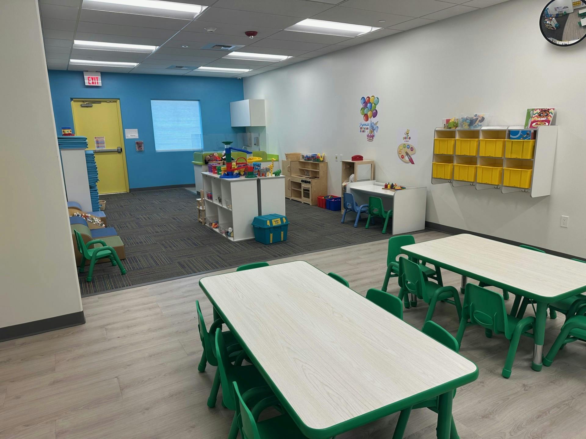 An empty childcare classroom with small tables and chairs