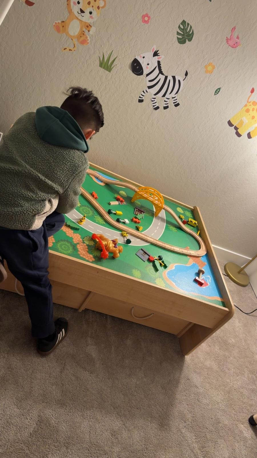 Child playing with a toy train set on a play table