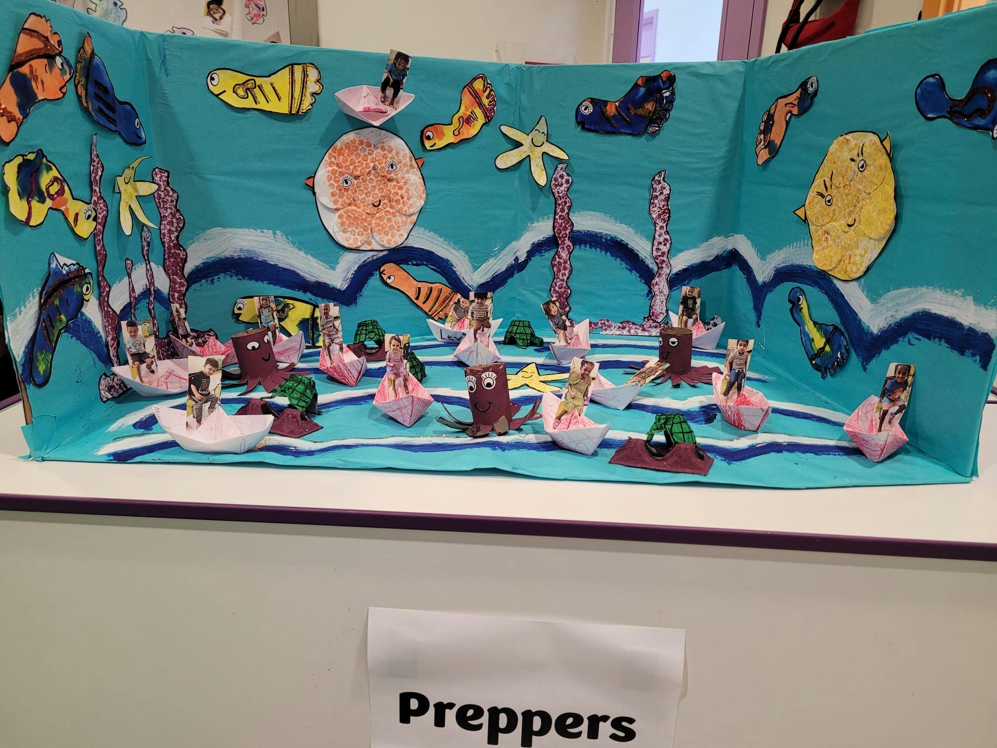 Children's art project with cutout sea creatures and photos of children in boats