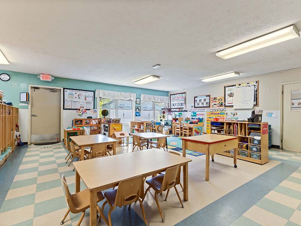 Empty classroom with small tables and chairs, and learning materials