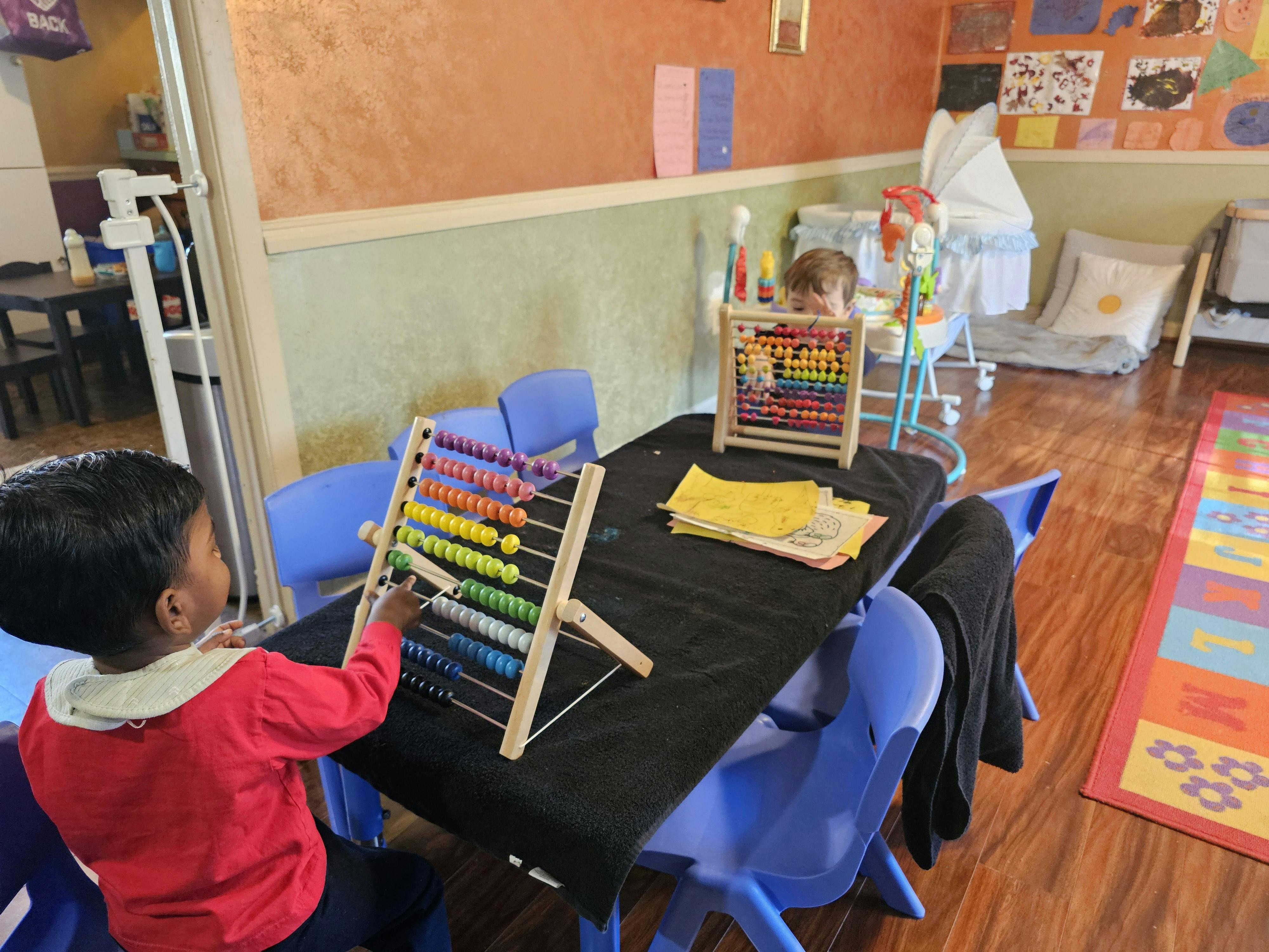 Child playing with an abacus at a table