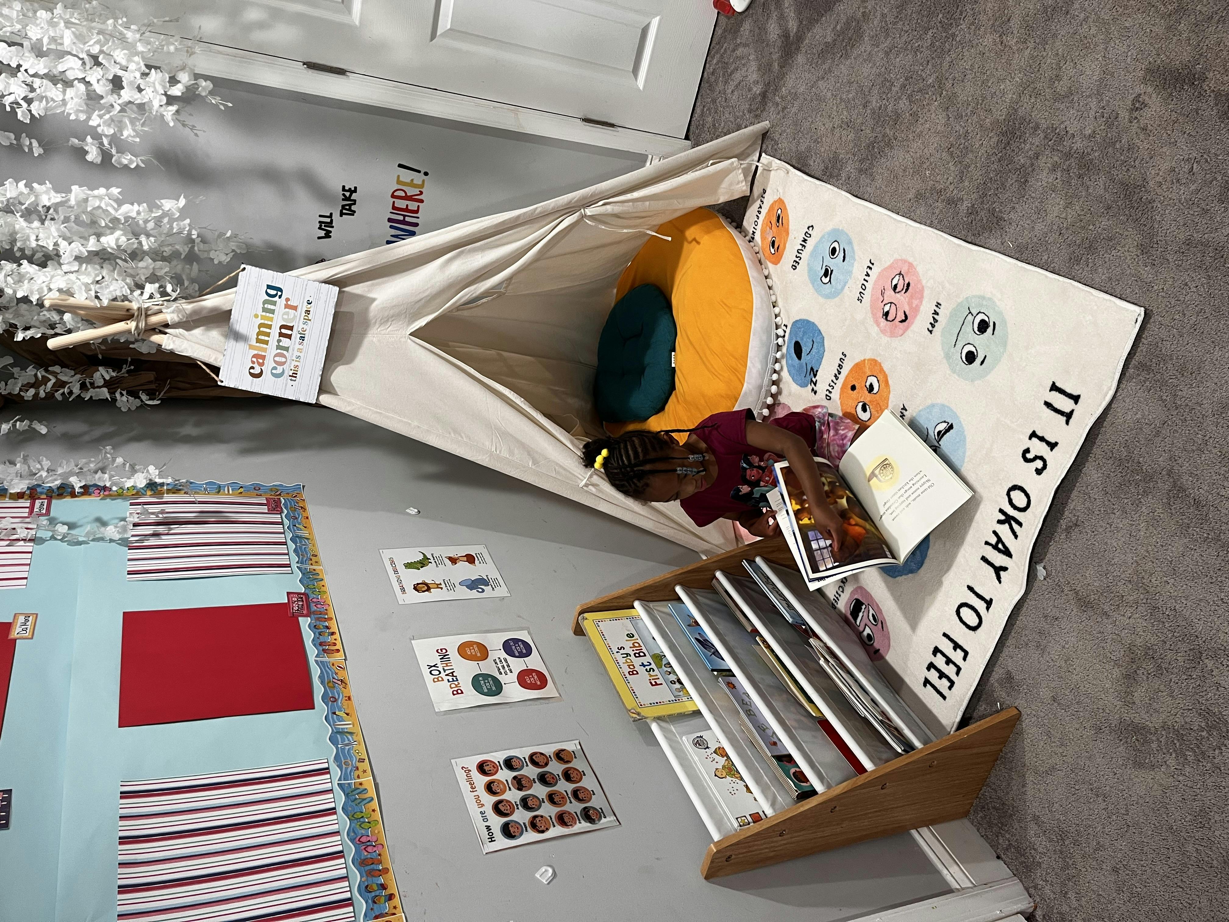 Child sitting inside a teepee tent with a book