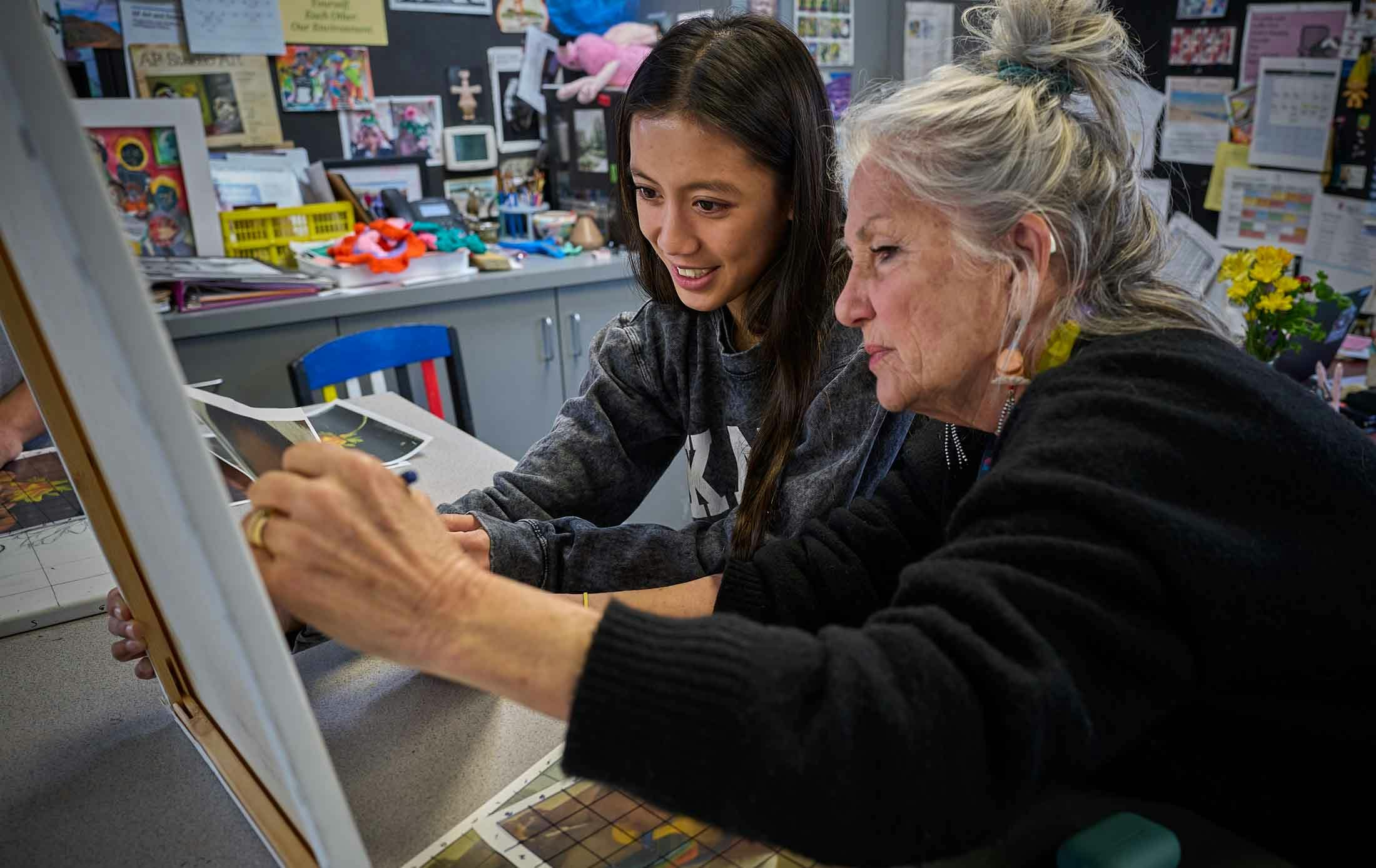 Adult and teen looking at artwork in a classroom