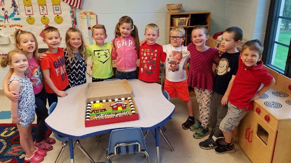 Group of children standing around a table with a cake in-box cake
