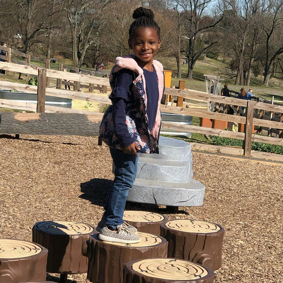 Child standing on a tree stump at a playground