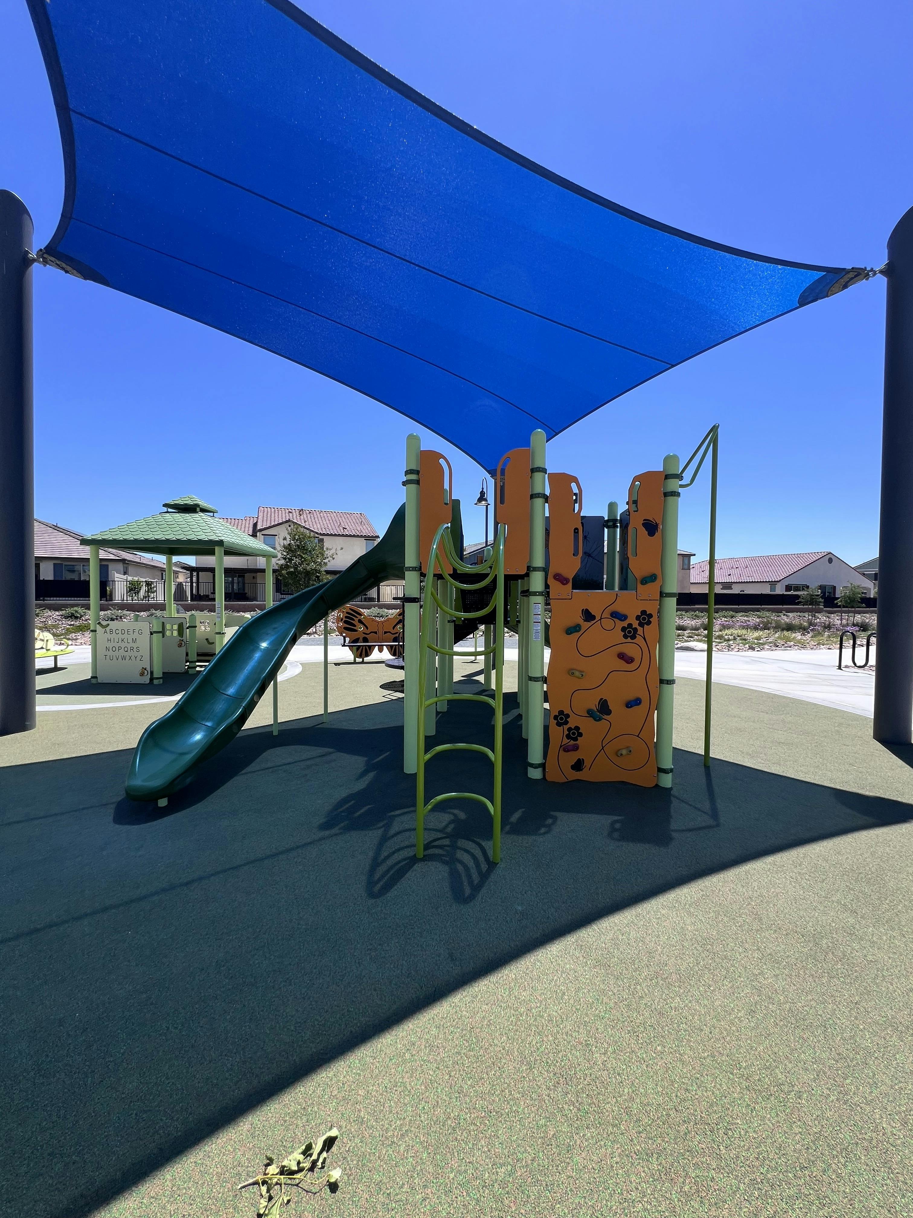 Playground with slides, climbing wall, and a blue shade canopy