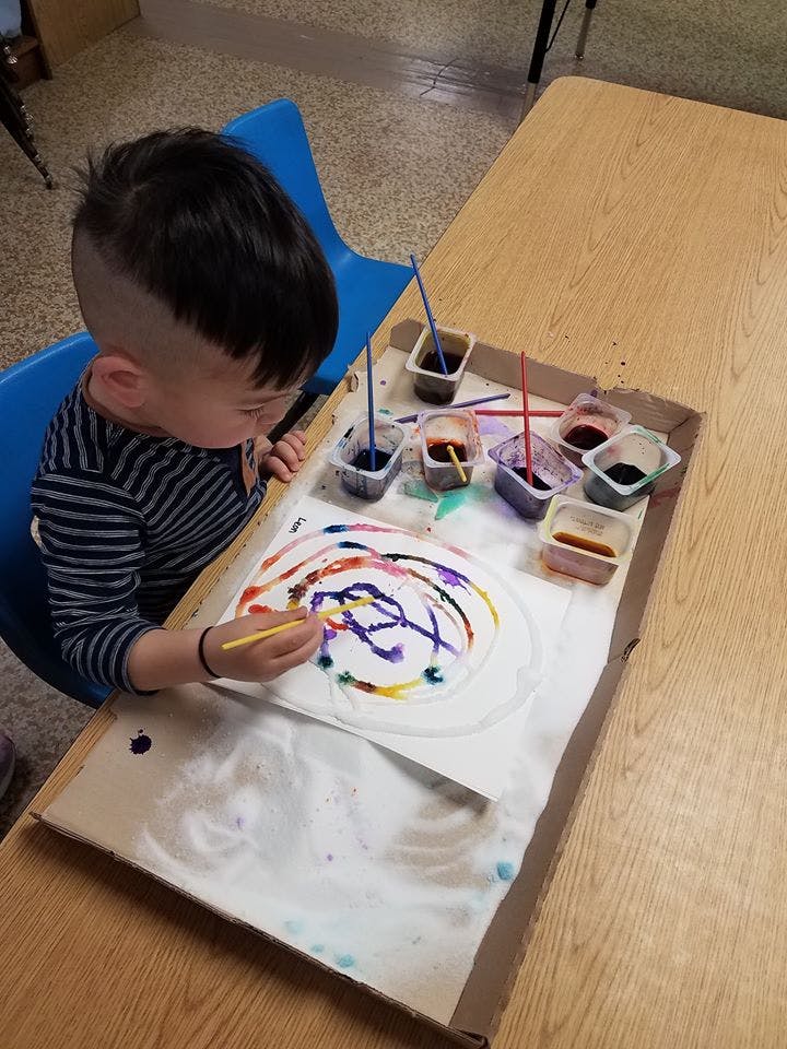 Child painting with colorful dyes on a paper plate