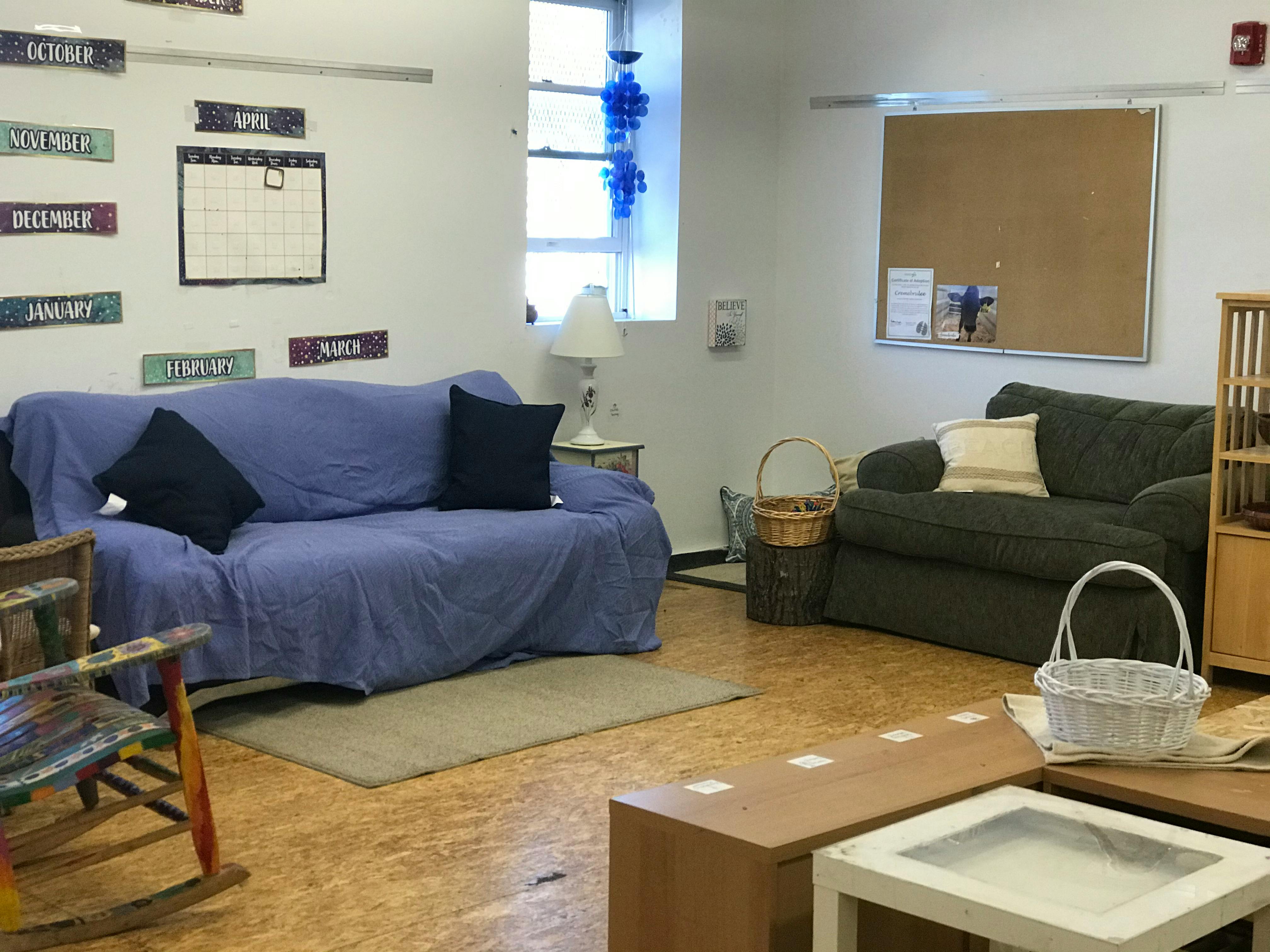 Living room with two couches, a rocking chair, and a bulletin board